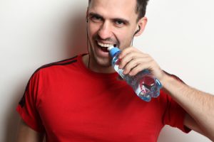 Man Opening Water Bottle with Teeth