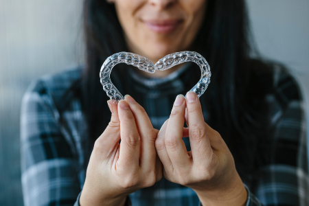 Patient Making Heart Shape with Dental Aligners